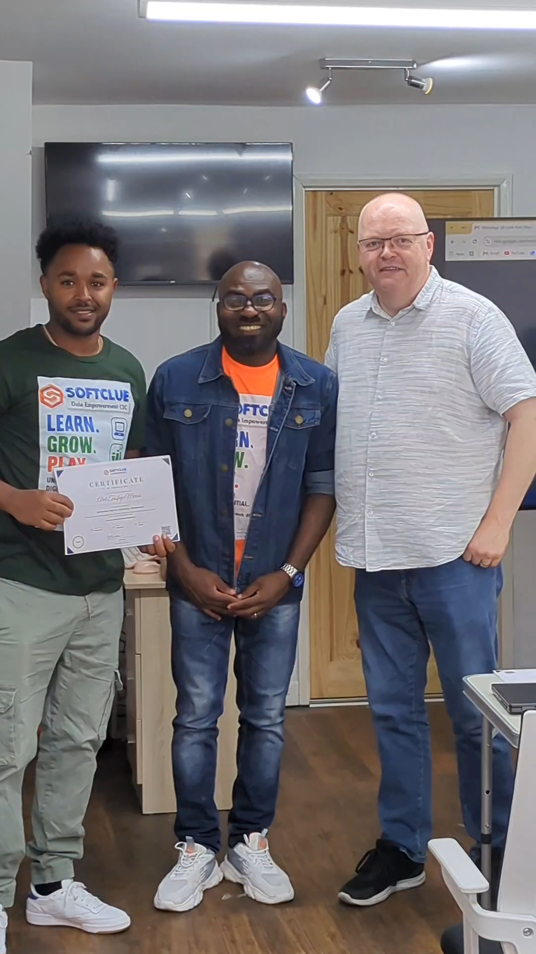 Graduate proudly holding his certificate with the programme team